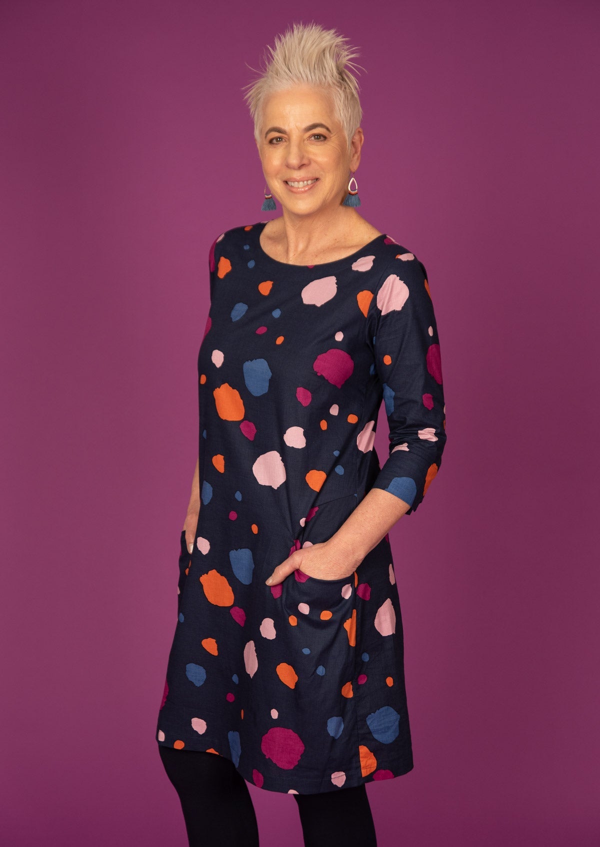 Model standing with hands in pockets wearing 100% cotton dress in bold and colourful printed dress.