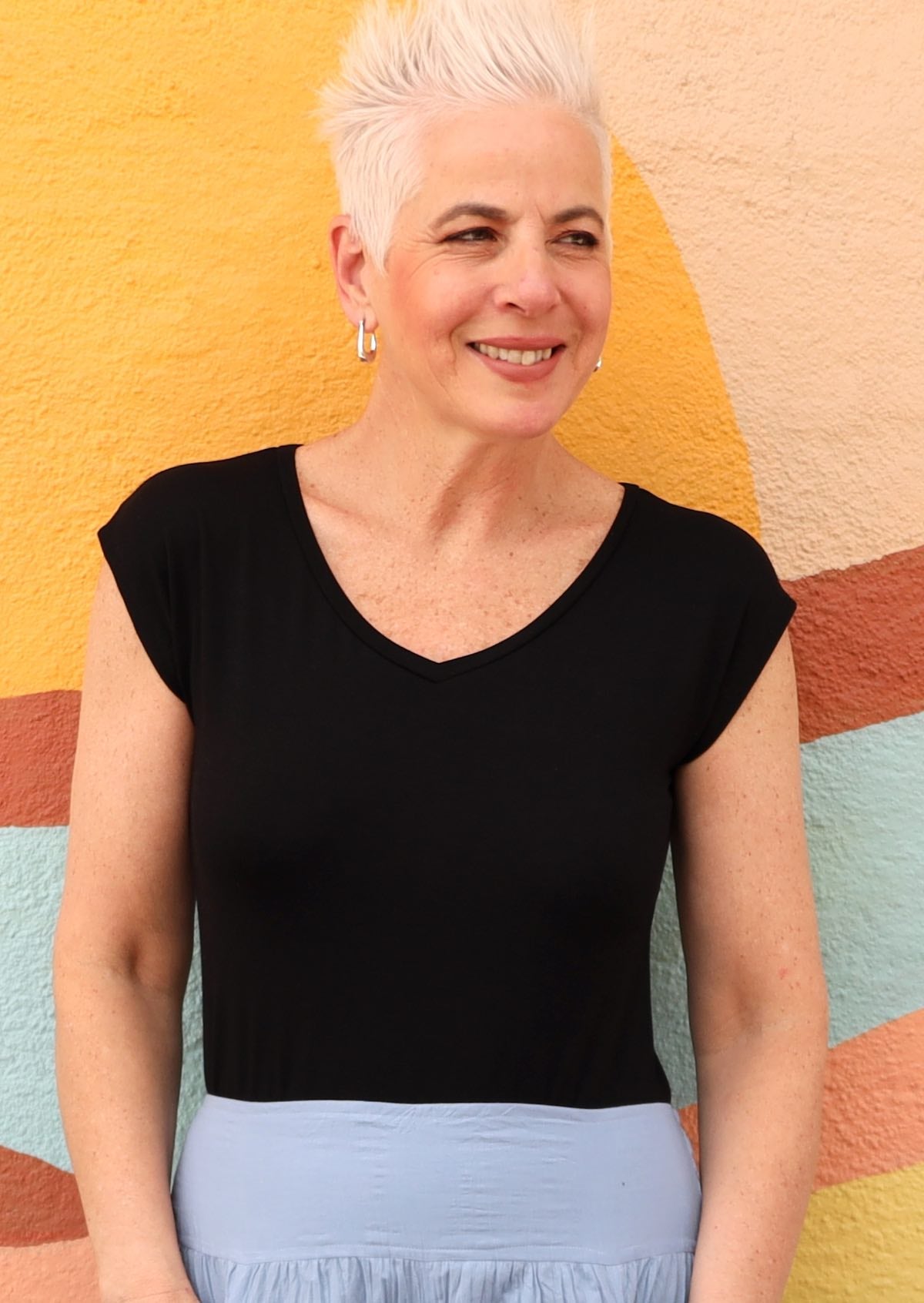 Woman with short blonde hair wearing a black v-neck short cap sleeve rayon top