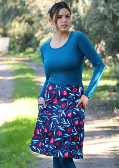 Model wears 100% cotton knee length skirt with pockets and a pink red fruit print on a blue base