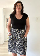 Woman wearing a black t-shirt and 100% cotton skirt with pockets indoors.