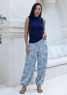 Woman wearing white based blue floral cotton harem pants paired with a sleeveless navy blue top