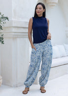 Woman wearing blue and white floral cotton wide leg pants with buttoned ankle paired with navy sleeveless top