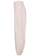 Side view of relaxed fit white cotton pants with pockets, elastic waist and buttoned ankles