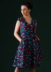 Woman wears navy dress with a red fruit print.