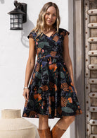 Woman wearing floral knee length retro style dress with cross over bodice and cap sleeves.
