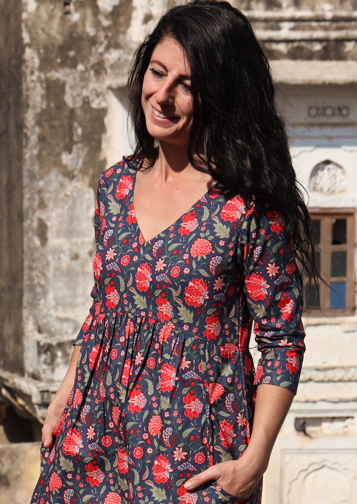 Close up of woman wearing 3/4 sleeve cotton dress with V-neck and small gathers under the bust in empire waistline