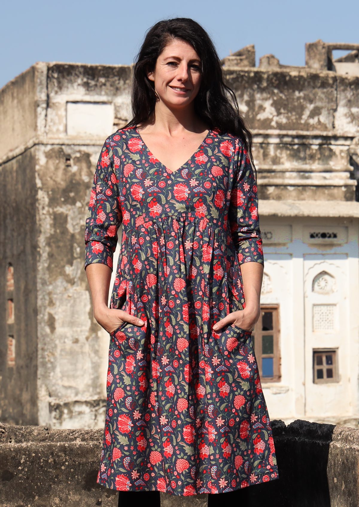 Woman wears cotton 3/4 sleeve V-neckline over the knee length dress with hands in pockets