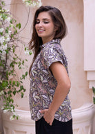 Side pose of model wearing short sleeve relaxed fit cotton top with V-neckline, collar and folded cuff sleeves.