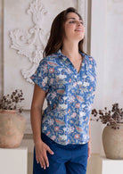 Model wears short sleeve relaxed fit cotton top with coral pink, sage green and lemon yellow florals on dusty blue base.