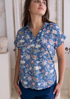 100 percent cotton relaxed fit dusty blue based floral top with short folded cuff sleeves, collar and V neckline