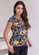 Model standing against the white background wears tailored retro floral top in black with yellow and grey floral print.
