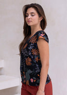 Woman wearing a 100% cotton black tailored top with cap sleeves and round neckline.