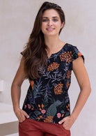 Woman wearing a dark floral cotton top with cap sleeves, round neckline with keyhole cutout and length upto the hip.