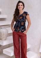 Woman wears 100 percent cotton floral printed tailored top with rust cotton pants