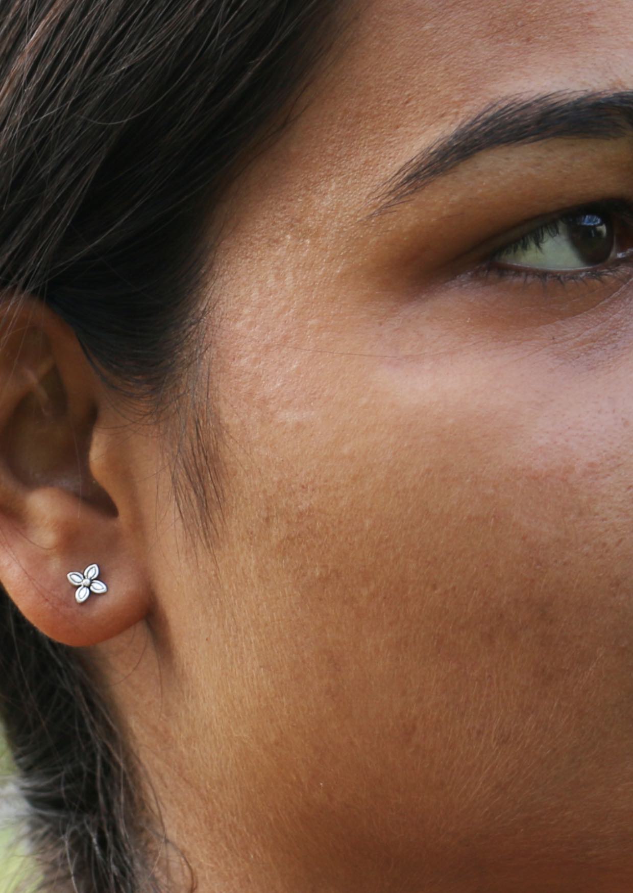 Close-up of woman’s ear wearing Baronia sterling silver studs with four curved petals and silver butterfly backs