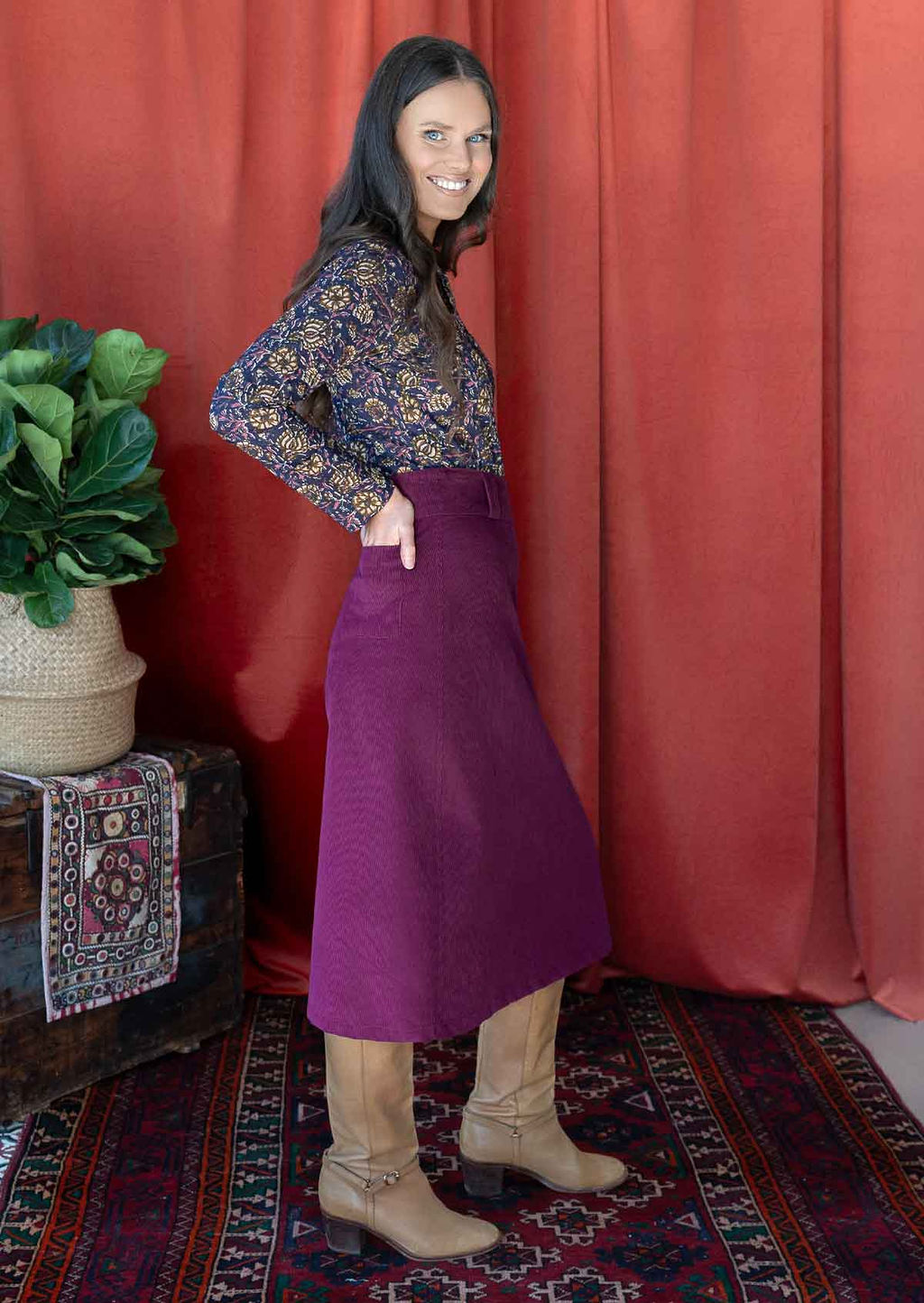 woman wearing purple corduroy aline skirt  with purple cotton top hand in back pocket