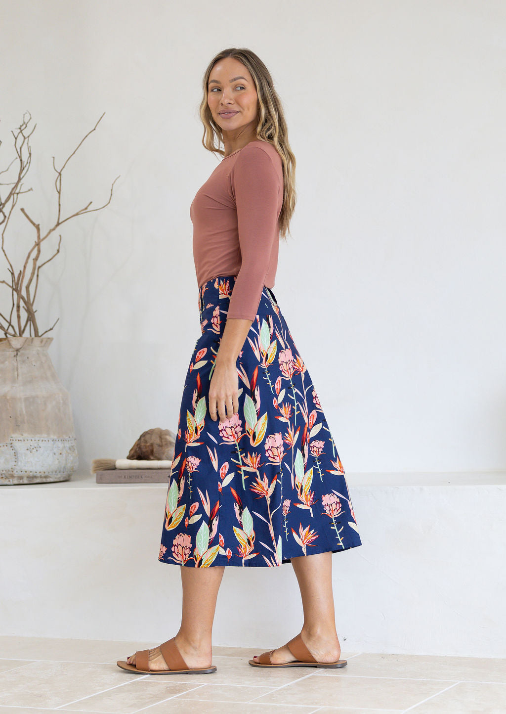 Woman wearing floral print navy blue midlength skirt with side zipper and belt loops.