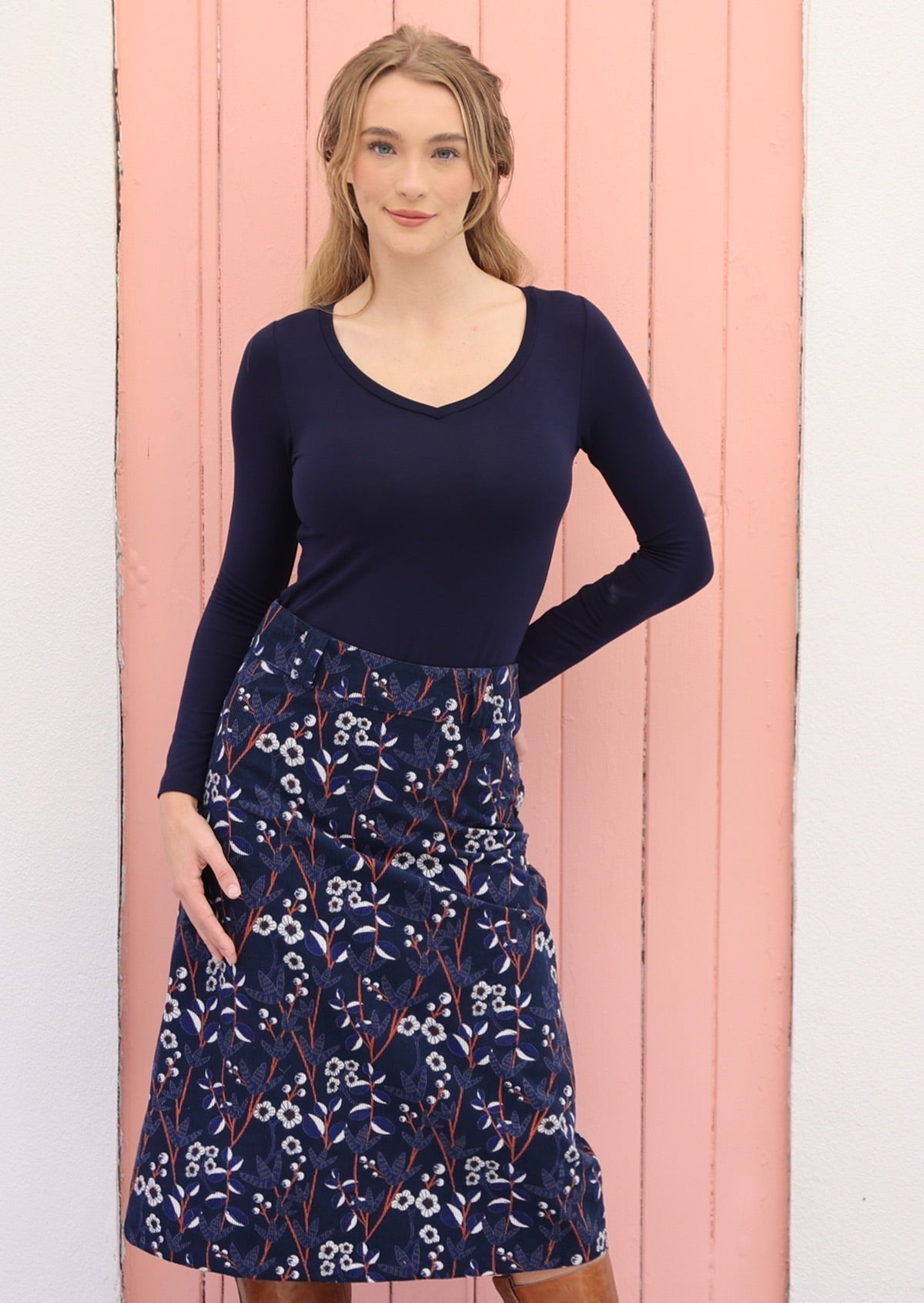 Model wears mid length corduroy skirt with belt loop, side zipper and back pockets.