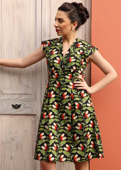 Model wears green and black cotton dress with cap sleeves
