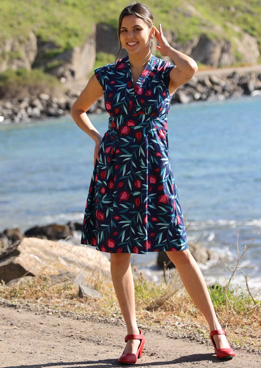 Model wears 100% cotton classic style knee length dress with a blue and red fruit pattern. The V neck dress has an a-line skirt, cap sleeves and a side zip.