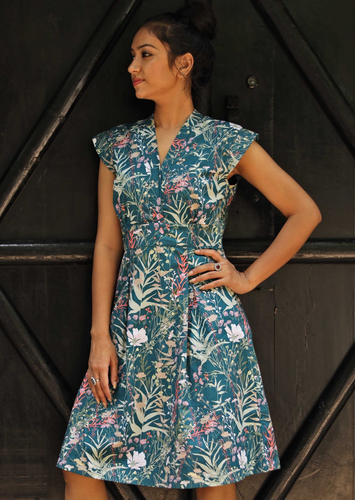 Woman wearing the Billie Dress Verdure, a structured cotton sundress with cap sleeves and a teal wildflower print.