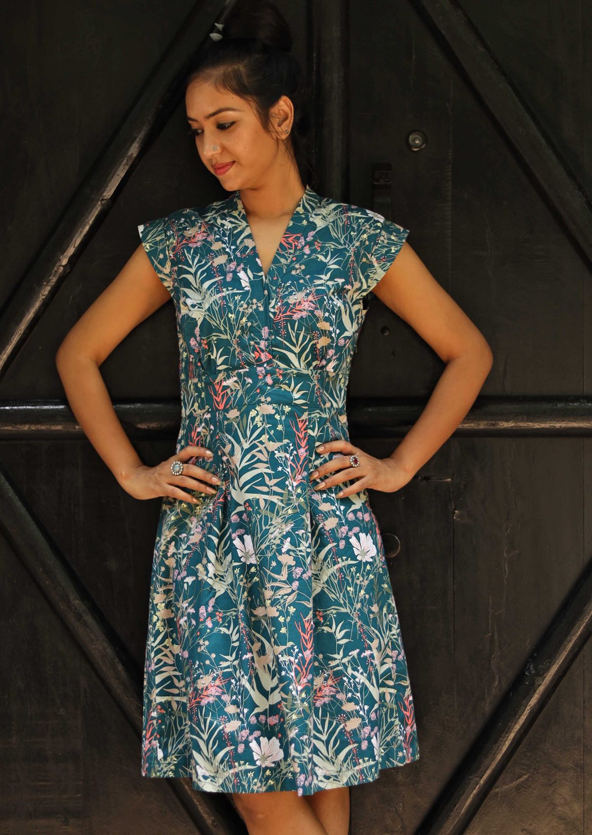 Woman wearing the Cotton Billie Dress Verdure, a structured cotton sundress with cap sleeves and a teal wildflower print.