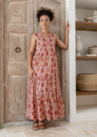 Model wears cream based warm floral cotton dress with pockets, sleeveless, V neck and mandarin collar.