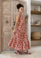 Model stands sideways wearing a 100% cotton 3 tiered maxi dress with flowy skirt, 3/4 sleeves, buttoned bodice and pockets.