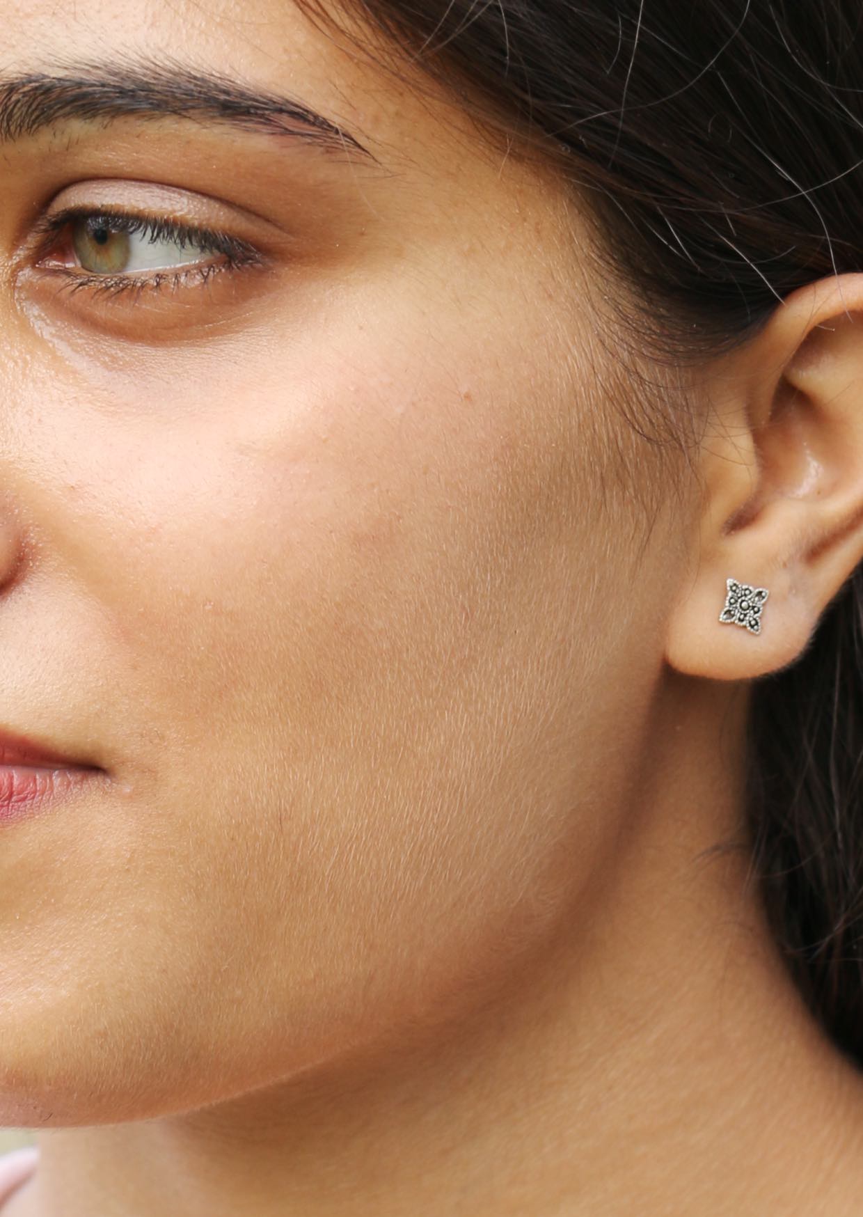 Close up of a woman wearing a small square shaped boho blooms silver studs with delicate floral design