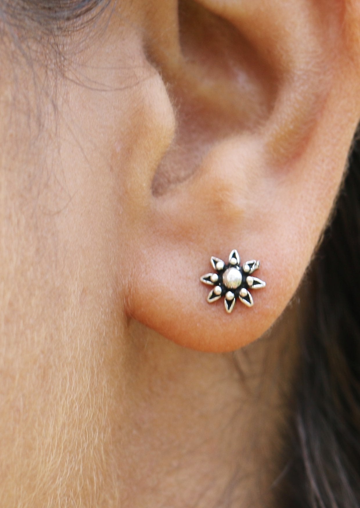 Close up of an ear wearing a Boho Silver Flower Studs featuring intricate floral design