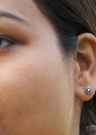 Close up of a person wearing a floral stud earrings with delicate floral design 