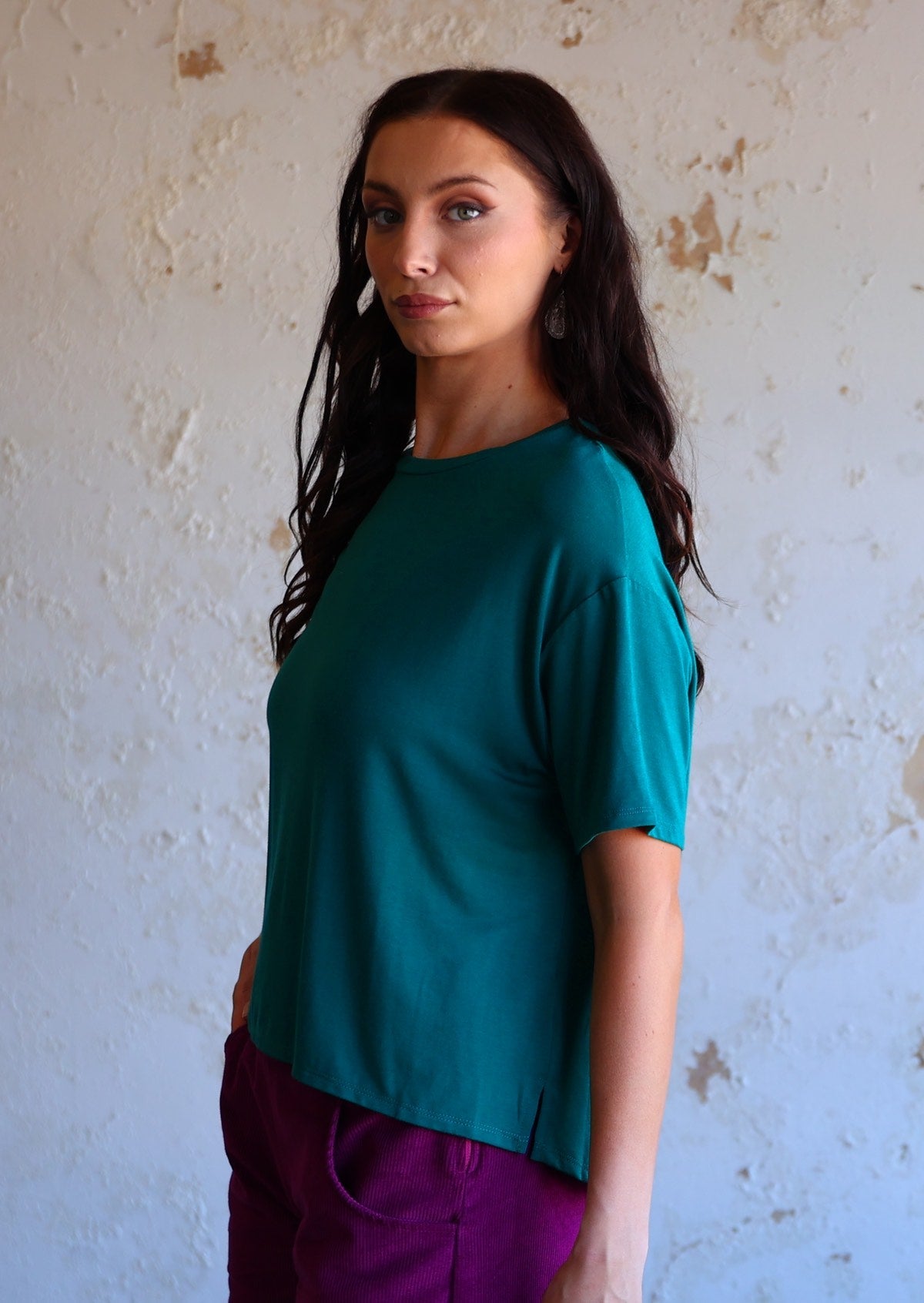 woman standing side-on wearing loose fit teal blue t-shirt made of rayon