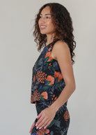 Woman wearing a sleeveless floral top with side bust darts, against a plain background