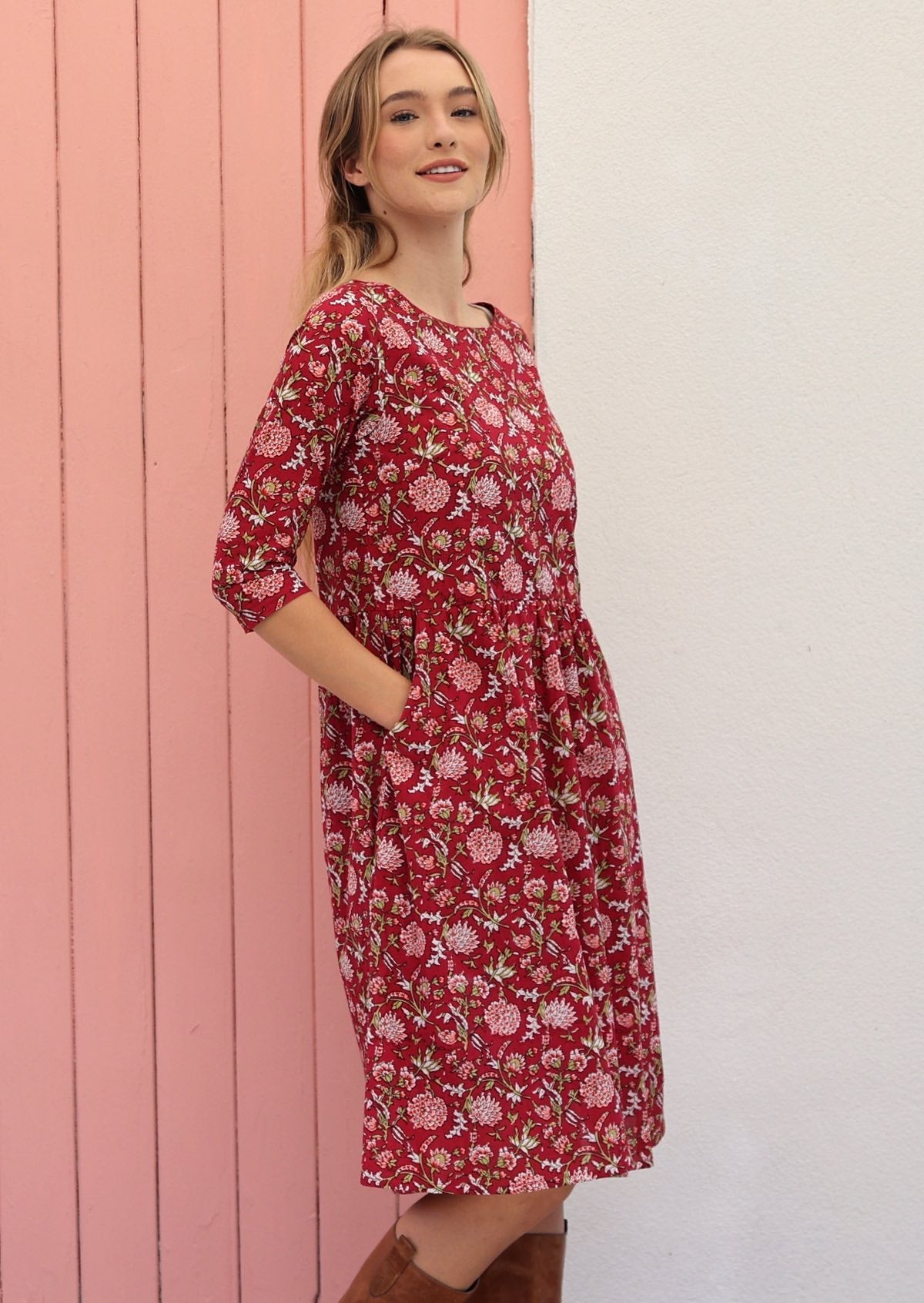 Model wears knee length cotton dress with hands in the pocket and 3/4 sleeves.