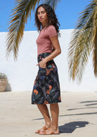 Side pose of model wearing knee length pencil skirt with top stitch detailing, pockets and hidden side zipper