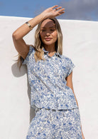 Woman wearing a blue floral print button up cotton shirt in a natural setting.