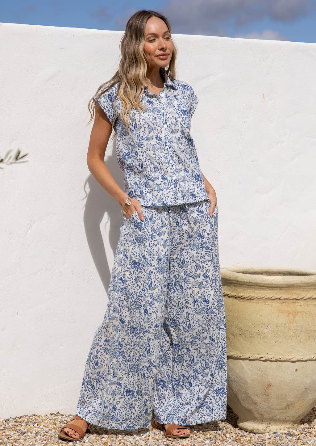 Woman wearing a blue floral print cotton shirt which is 100% cotton against a white background.