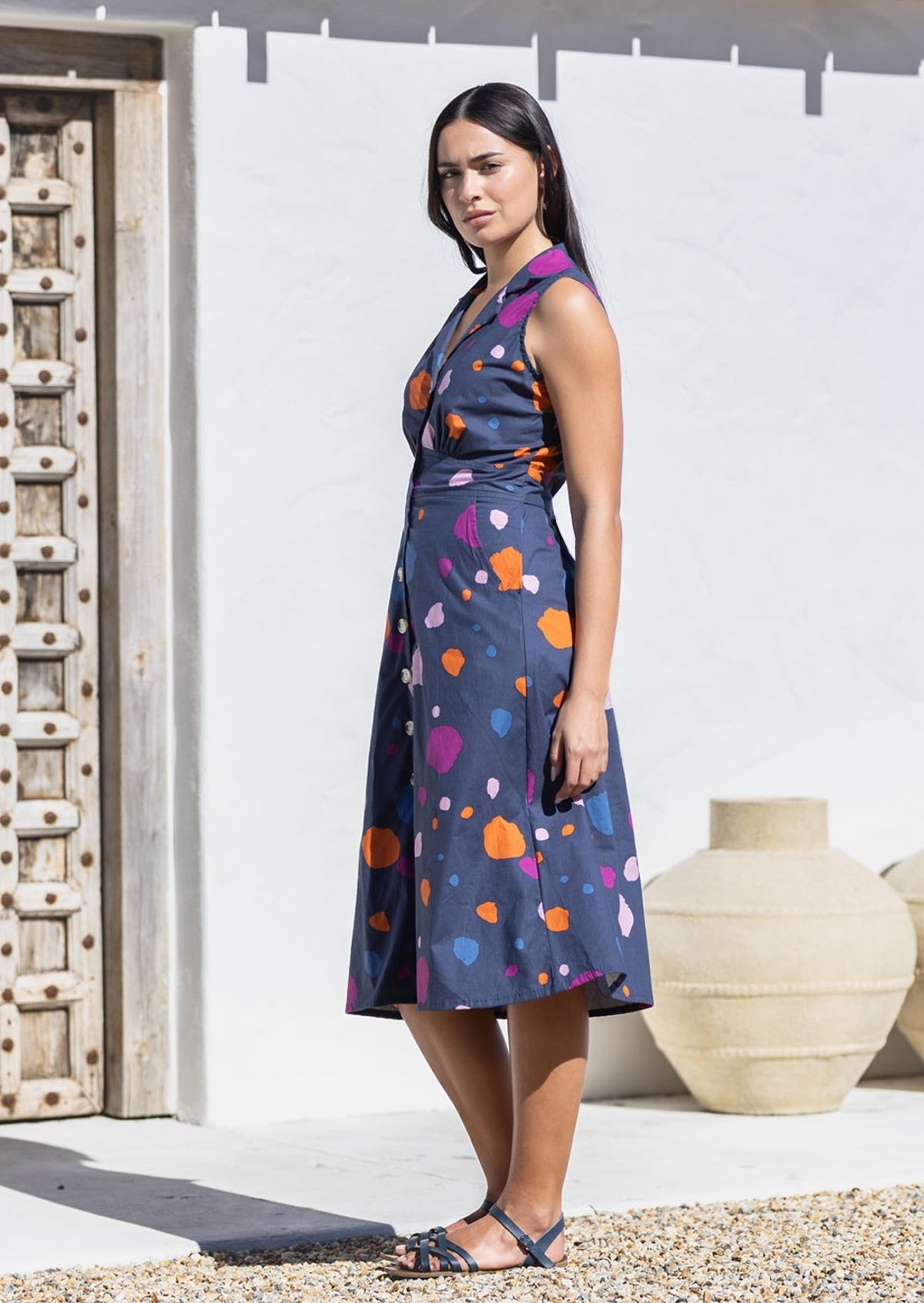 Model standing in sun wears A line, button through cotton dress with collar and gathers under the bust.