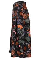 Side view of black cotton skirt with botanical print in pink, orange, blue and green, featuring box pleats and side pockets