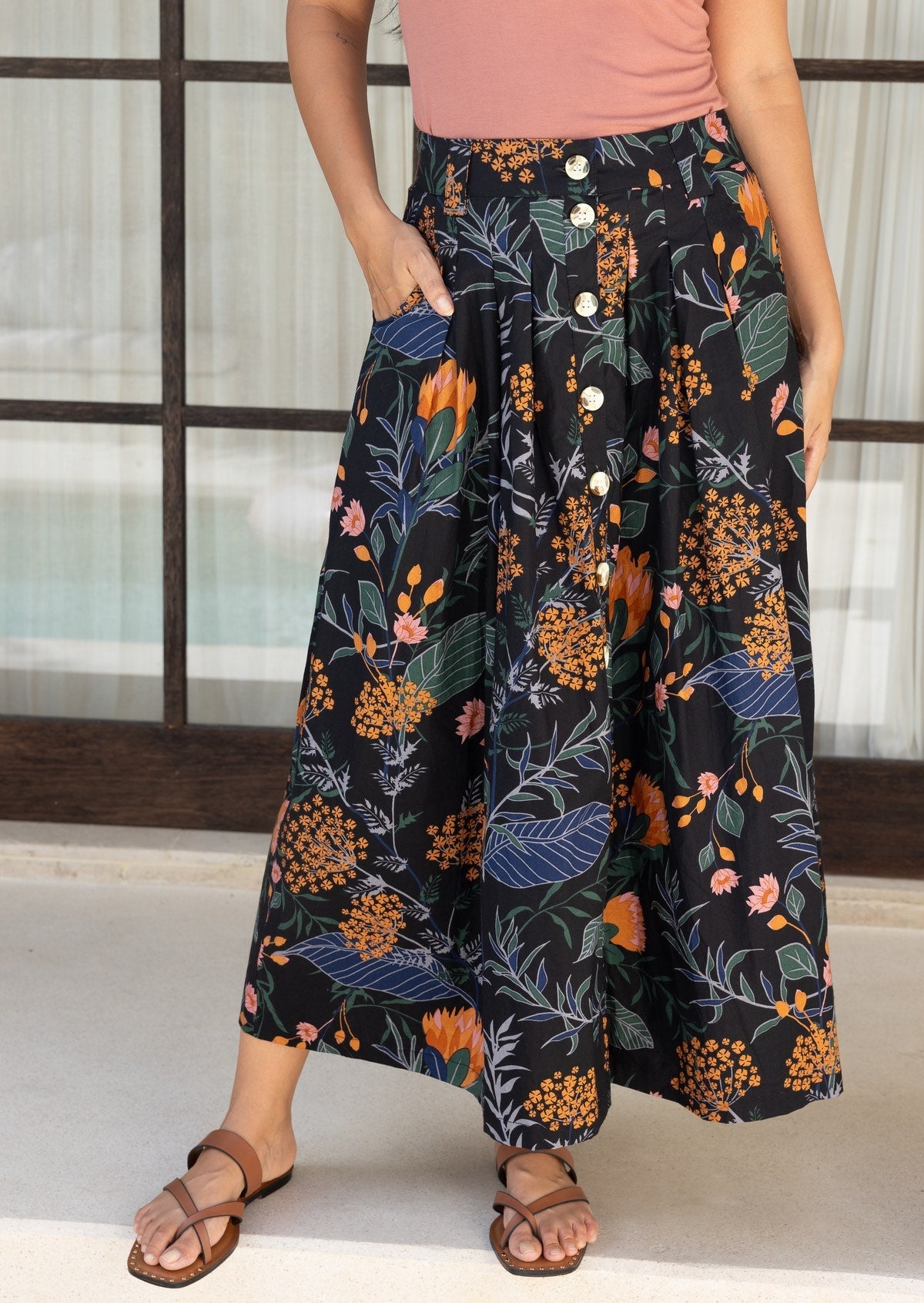Close up of a cotton button through skirt in a black based floral print, with front pockets