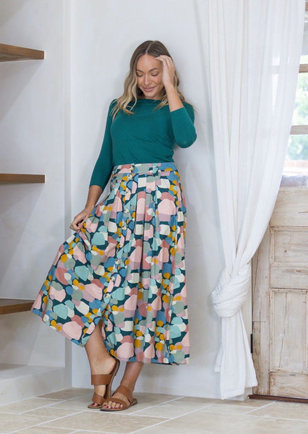 Woman wearing a stretch rayon green top and pastel print button through cotton shin length skirt