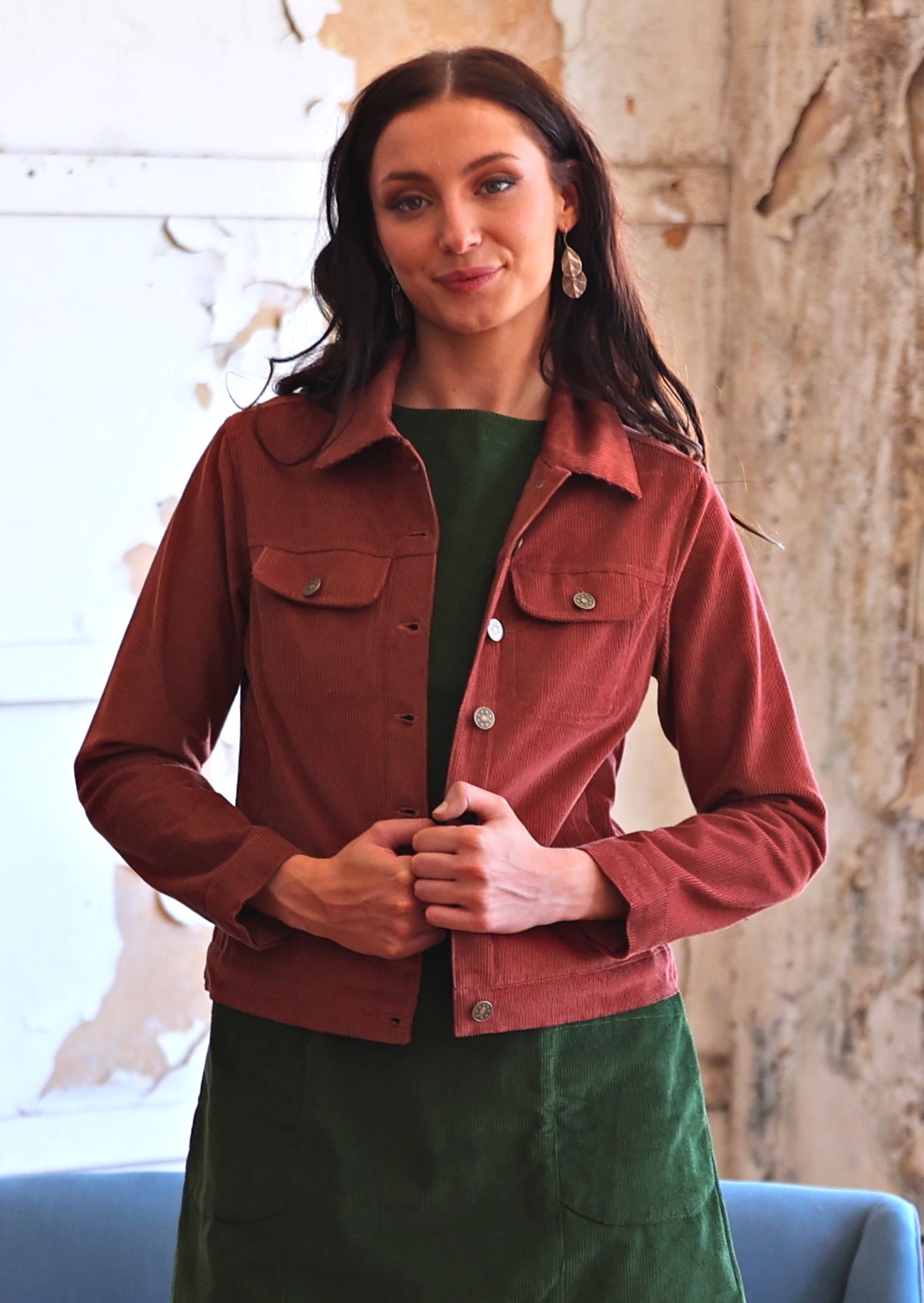 Woman in rust coloured cotton corduroy jacket over green corduroy dress