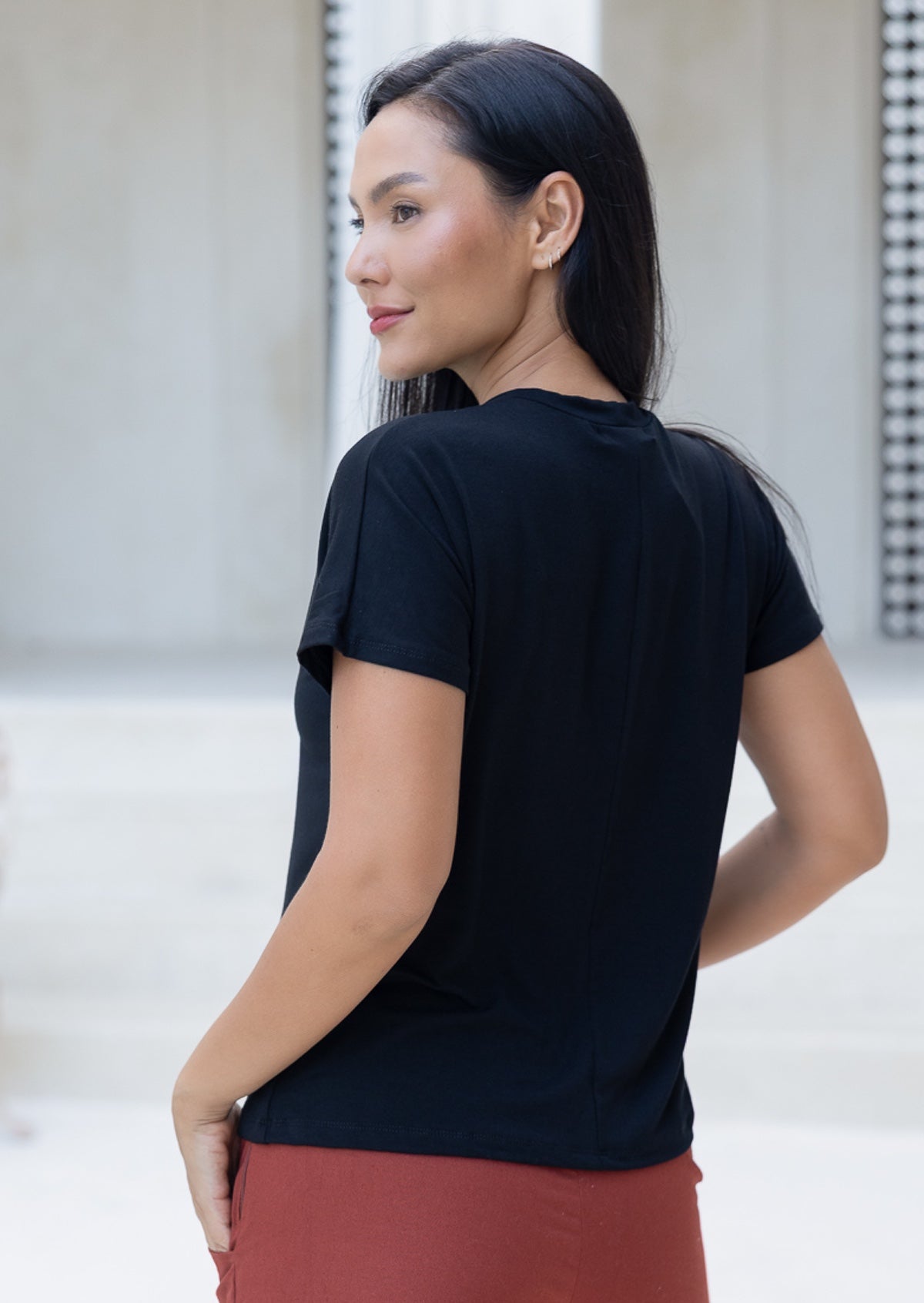 Rear view of woman wearing a black t-shirt and rust coloured pants