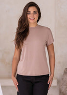 Woman wearing a fawn t-shirt with a high crew neckline and black pants