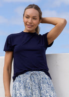 Woman wearing a navy blue t-shirt and floral skirt against a blue sky.