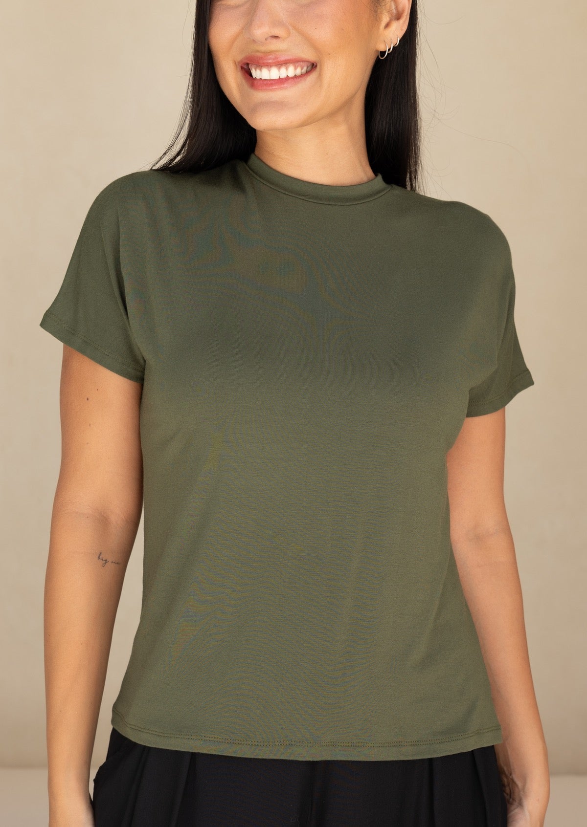 Woman wearing an olive green stretch rayonn t-shirt against a beige background