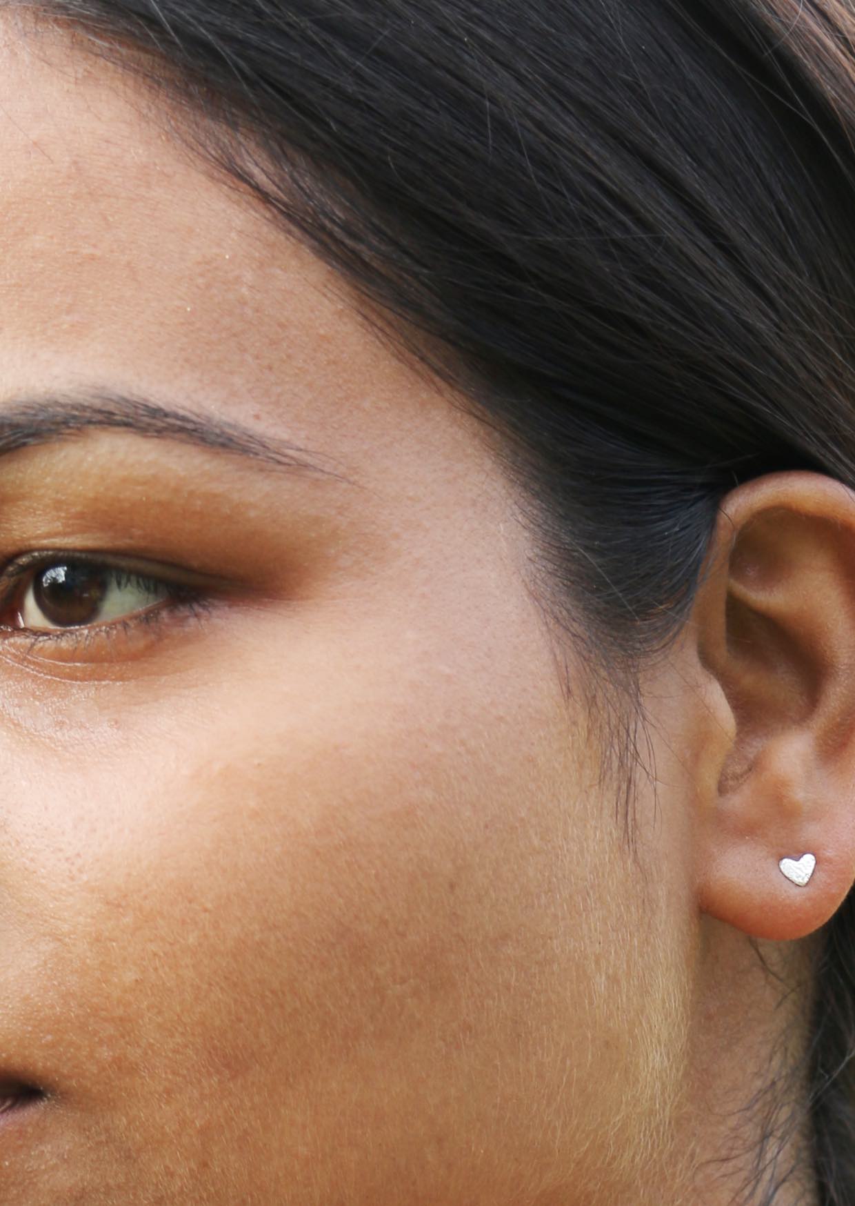 Close-up of a person wearing a heart-shaped studs with intricate texture design
