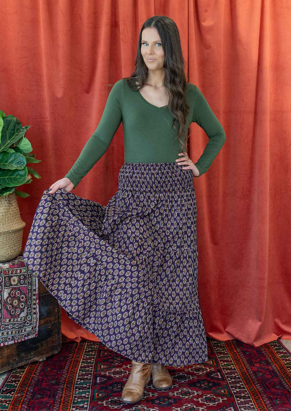 Woman wears floral print cotton skirt with wide elastic waistband, paired with long sleeve V neck top green.