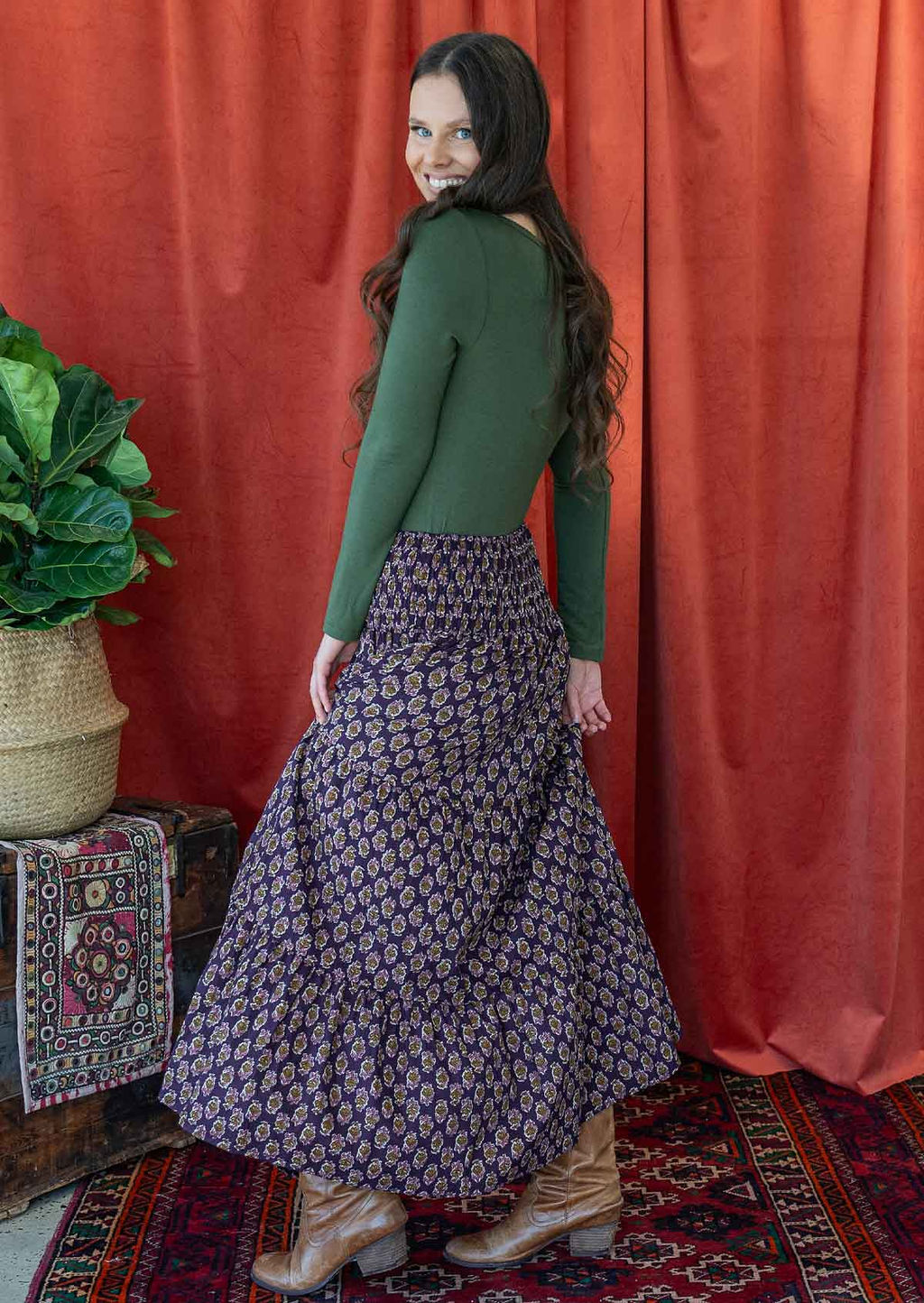 Woman posing sideways wearing a beautiful floral printed cotton skirt with tiers and wide shirred waistband.