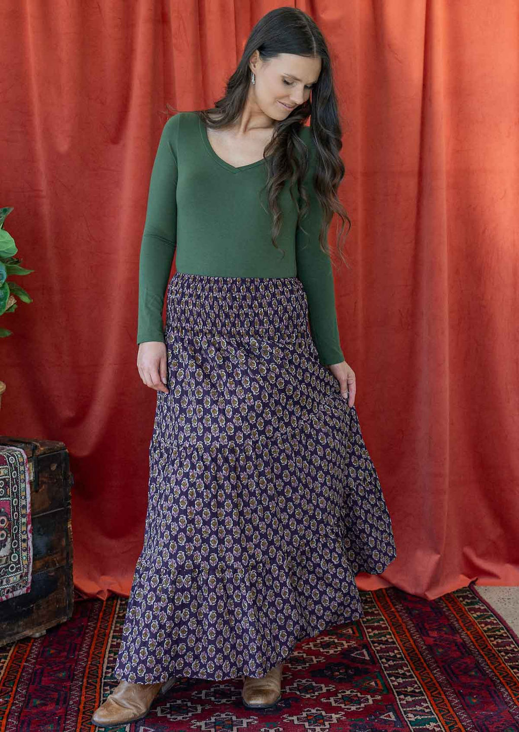 Woman wears cotton maxi skirt with pink, cream and brown floral print on dark purple base.
